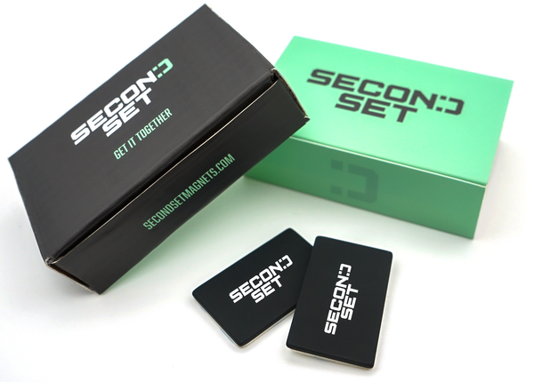 Second Set product packaging featuring a black box with a sleeve labeled 'Second Set' and two black rectangular Second Set magnets displayed beside it.