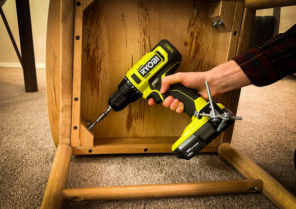 A person using a Ryobi drill equipped with a Second Set Magnet to assemble a wooden chair, with screws securely held by the magnet for easy access during the project.