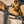 A DeWalt impact driver is being used to insert lag screws into a wooden stud, securing a TV mount. The Second Set magnet attached to the impact driver is holding onto additional lag screws for easy access. The person operating the tool is wearing protective gloves.