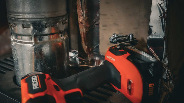 A Ridgid drill equipped with a Second Set Magnet holding screws, positioned next to metal ductwork, showcasing its utility in HVAC installation and repair.